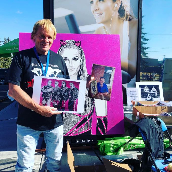 Former professional wrestler, Bruce Hart, holding Kim's oil paintings.