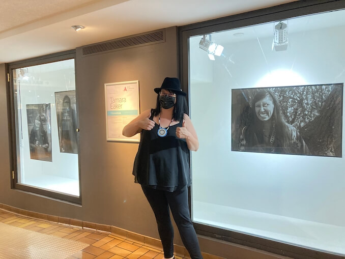 Tamara standing in front of her Exhibit in Arts Commons, showing August to September 2021. 