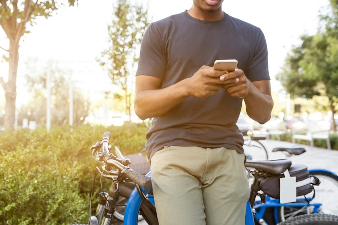 guy leaning against a bicycle on his phone