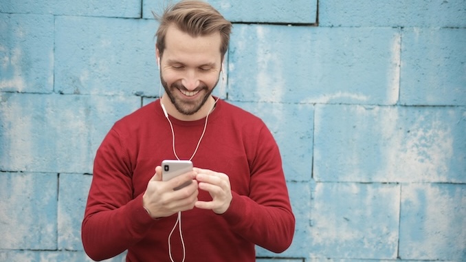 Man using a cell phone with a blue stone background.