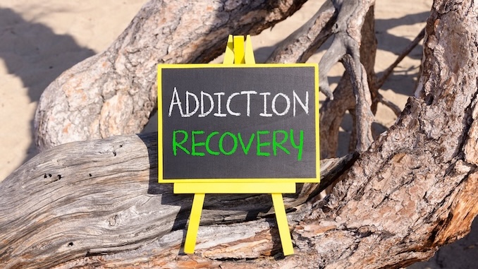 Addiction recovery symbol. Concept words Addiction recovery on beautiful black yellow blackboard. Beautiful old wood and sand background. Psychology addiction recovery concept. Copy space.