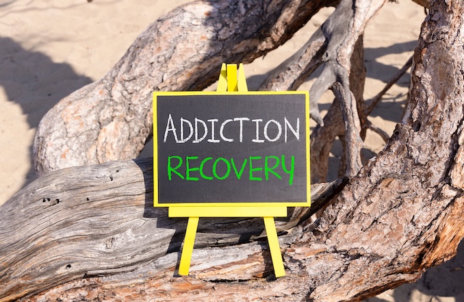 Addiction recovery symbol. Concept words Addiction recovery on beautiful black yellow blackboard. Beautiful old wood and sand background. Psychology addiction recovery concept. Copy space.